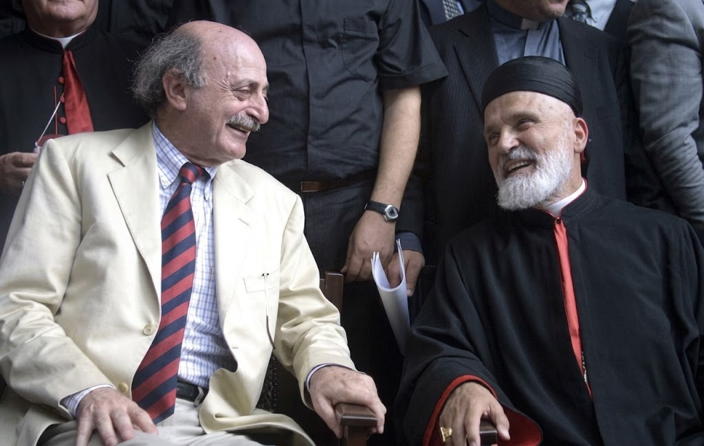 Walid Jumblatt and Maronite Patriarch Nasrallah Boutros Sfeir seated side by side, smiling at each other, at the Mountain Reconciliation gathering in 2001.