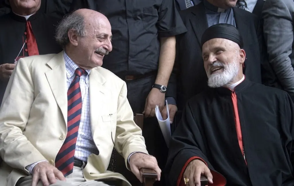 Walid Jumblatt and Maronite Patriarch Nasrallah Boutros Sfeir seated side by side, smiling at each other, at the Mountain Reconciliation gathering in 2001.